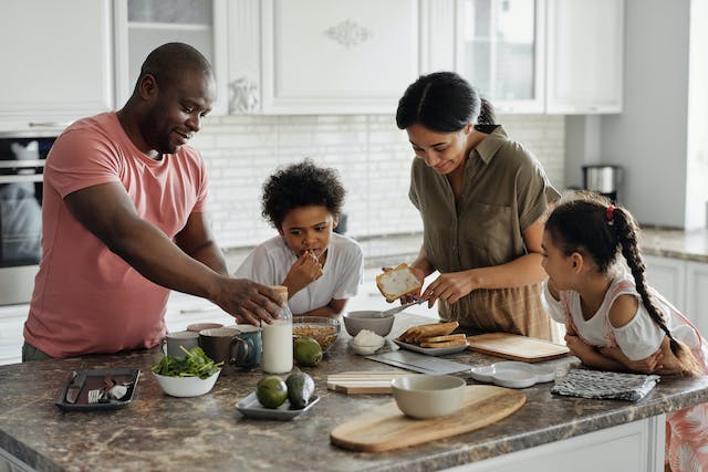 a family of four making food in the kitchen